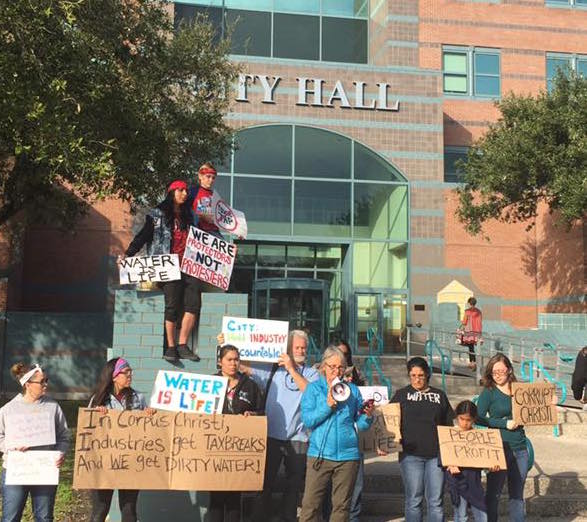 ~ Photo by Eli Poore ~ Image depicts demonstrators with For the Greater Good holding signs and chanting at the City Hall in Corpus Christi, Texas.