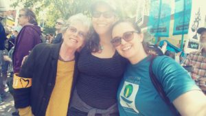 Pictured: UUMFE Treasurer Ellen McClaran, Office Administrator Sabrina Louise, and Program Director Aly Tharp smiling and hugging together for a photo at the #AllEyesonJuliana rally