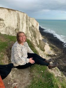 Zoe sitting on a cliff near the ocean.